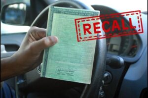 motorista com documento do carro na mão e escrito "recall"