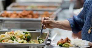 pessoa com roupa azul se servindo num restaurante por quilo