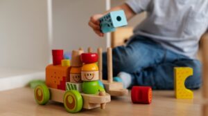 Criança brinca com trenzinho de madeira