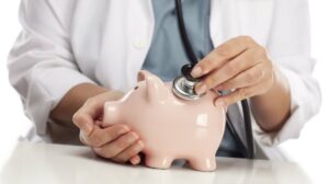 médico coloca estetoscópio em um cofre porquinho simulando aumento plano de saúde coletivo