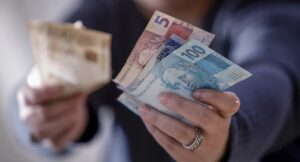 uma mão segurando notas de reais