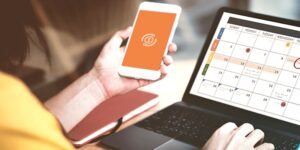 pessoa com agenda no computador e celular na mão