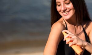 mulher passando no corpo protetor solar aerosol