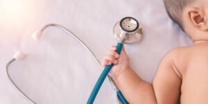 bebê segurando instrumento médico