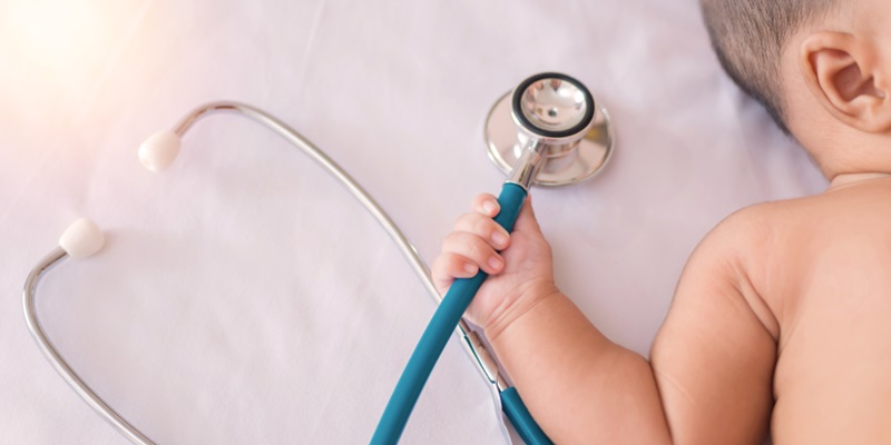 bebê segurando instrumento médico