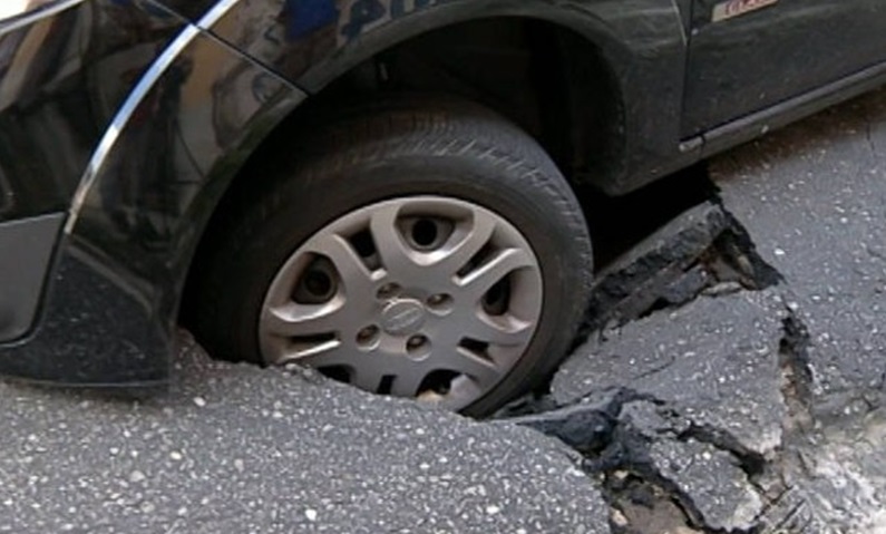 carro em buraco de asfalto