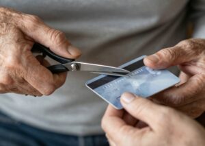 pessoa cortando cartão de crédito com tesoura