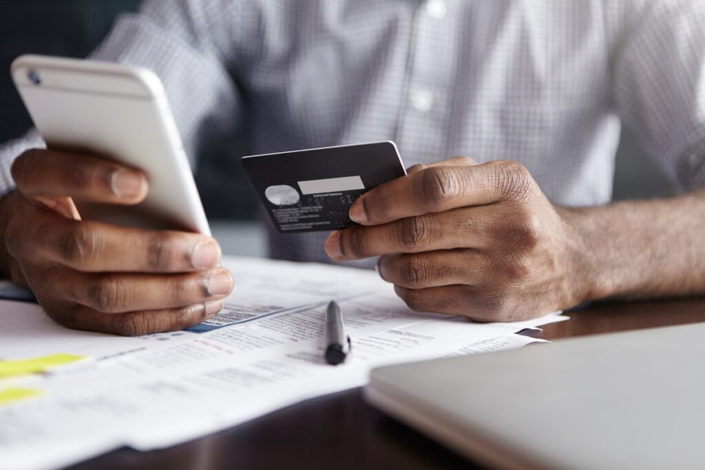 pessoa com celular e cartão de crédito na mão
