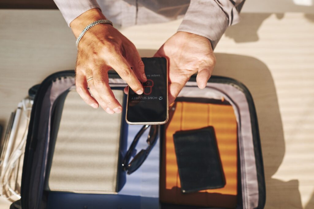 Viajante arrumanda mala e coloca celular e powerbank na mochila