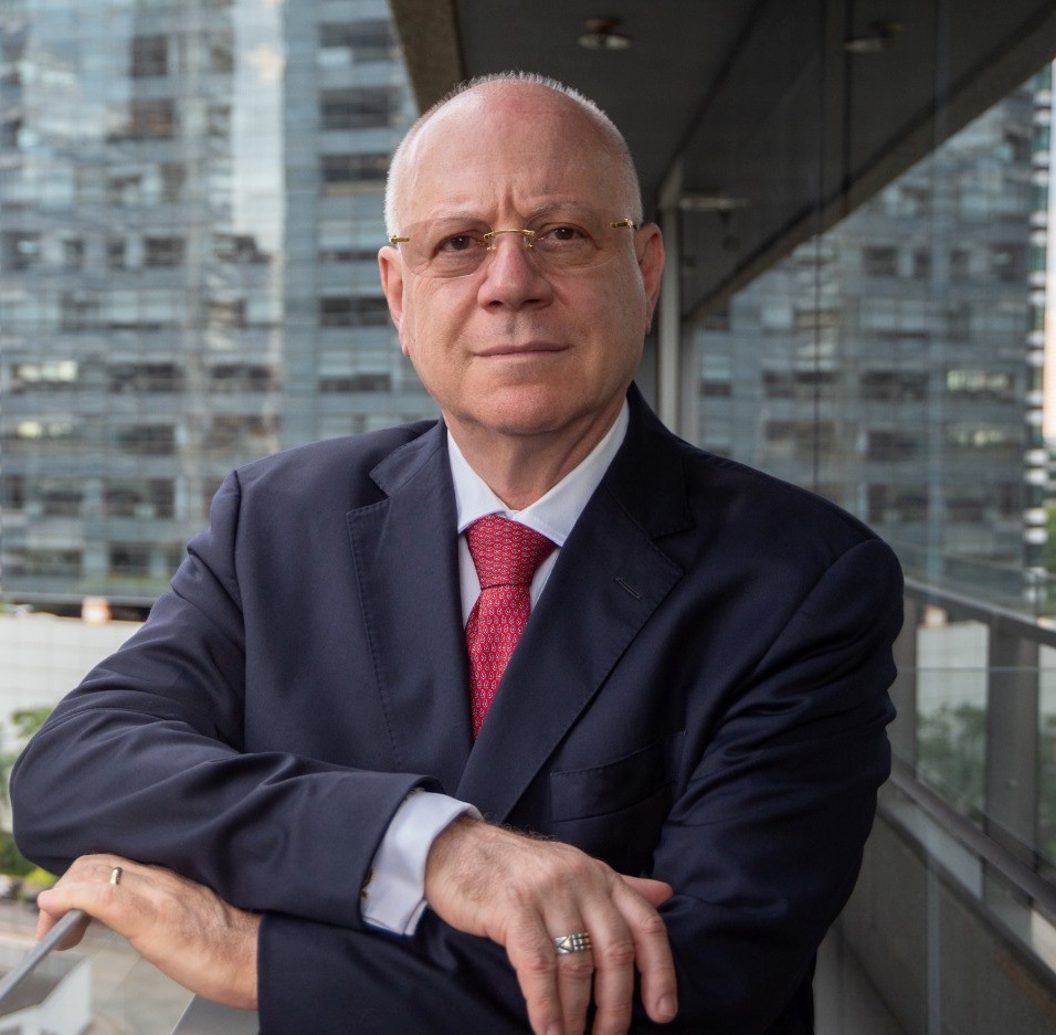 Elias efeir e presidente executivo da ANBC, usa óculos, está de terno azul, camisa branca e gravata vermelah. a foto foi tirada na sacada do prédio administrativo da ANBC